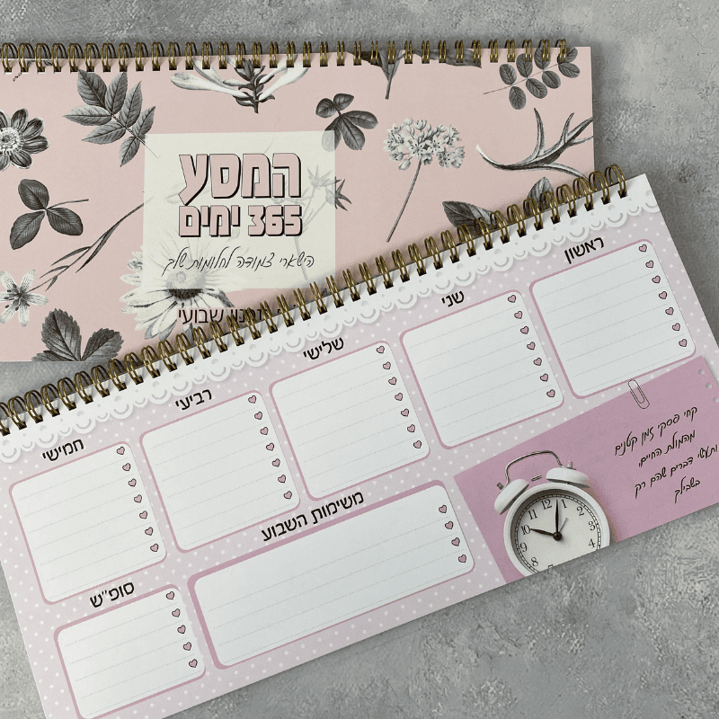 סט לוח תכנון שבועי ומחברת כריכה קשה | המסע 365
רקע ורוד עם פרחים לבנים ושחורים ספירלה מוזהבת
