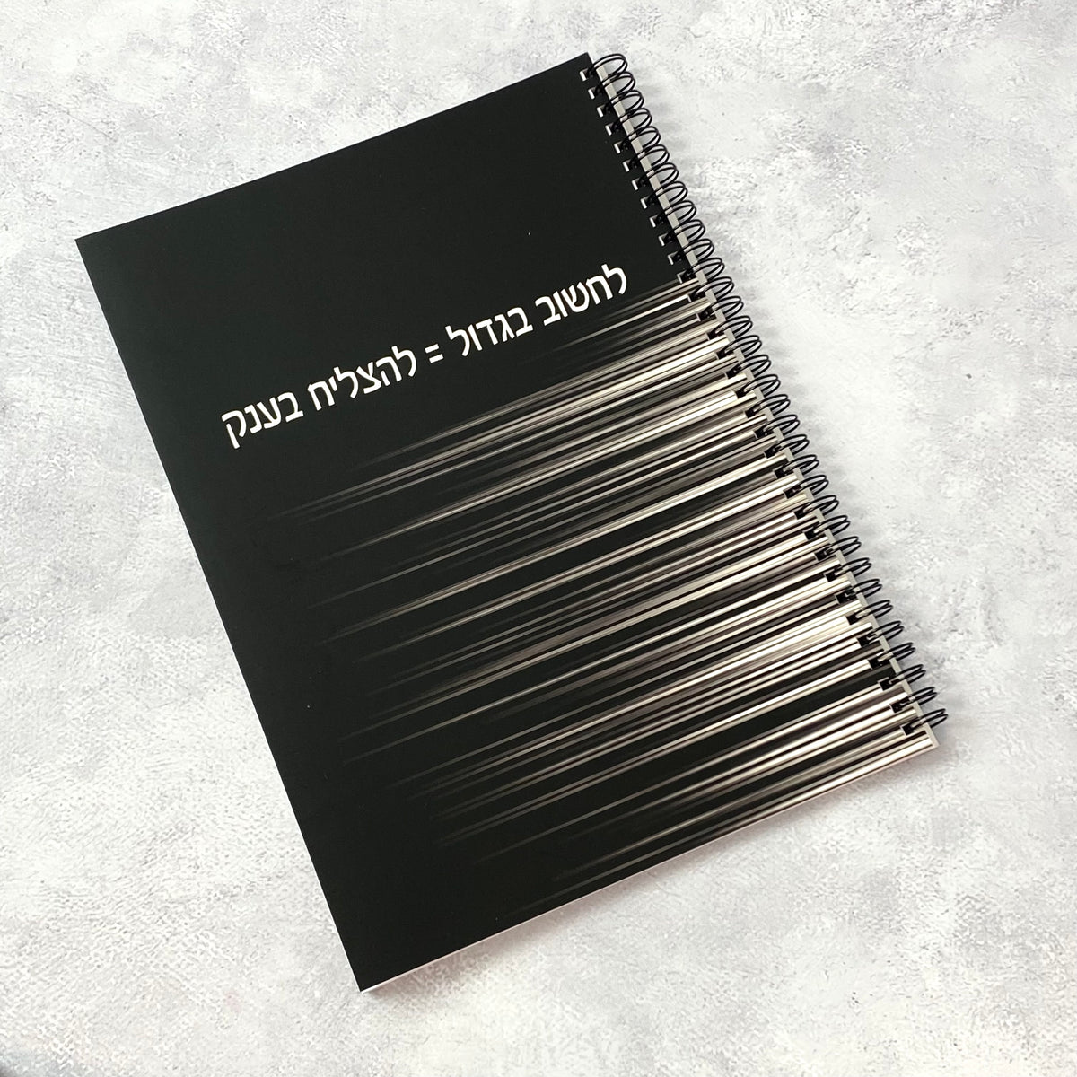 מחברת ספירלה גדולה לגבר ולאישה בצבע שחור עם הכיתוב: לחשוב בגדול להצליח בענק
