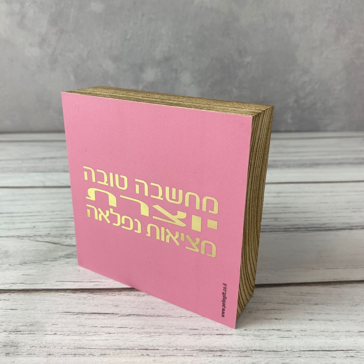 בלוק עץ אגוז ורוד ריבוע קטן עם הכיתוב: מחשבה טובה יוצרת מציאות נפלאה