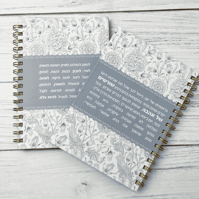 מחברת כריכה קשה דגם הצלחה צומחת מתוך אמונה עיצוב של פרחים שחורים על רקע לבן עם באמצע פס עבה אפור תכלת עם הכיתוב ספירלה מוזהבת