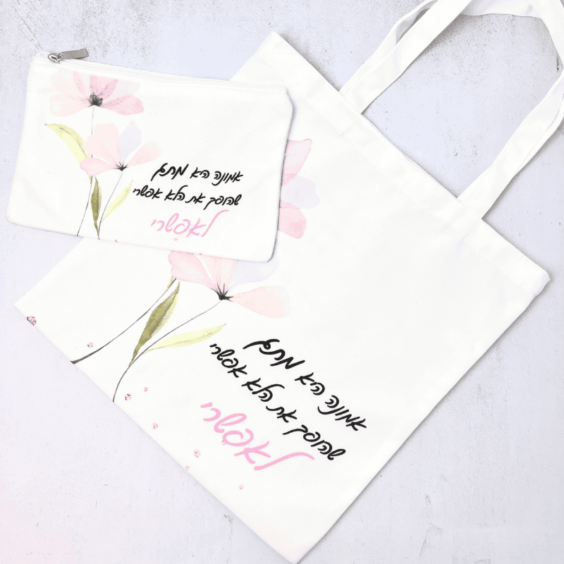 תיק קנבס עם משפט מעצים כיתוב בצבע שחור ורוד רקע לבן עם ציור של פרחים ורודים