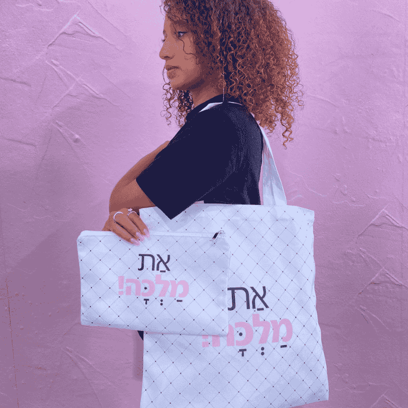 תיק קנבס דגם את מלכה בכיתוב ורוד שחור רקע התיק לבן עם נקודות דוגמנית מדגמנת את התיק