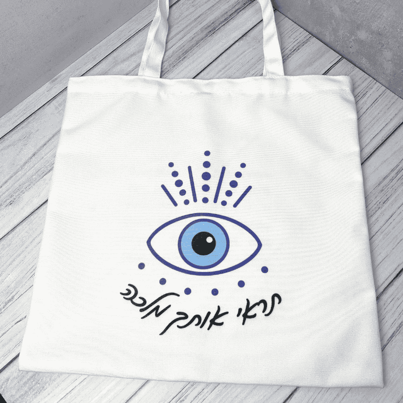 תיקי קנבס דגם תראי אותך מלכה כיתוב בצבע שחור תיק בצבע לבן ועליו ציור של עין כחולה